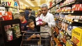 Nadim Fawzi Jouriyeh, a Syrian refugee who arrived recently in the United States with his wife and four children, puts items in a cart while shopping with his son, Farouq Nadim Jouriyeh, in El Cajon, Calif., Aug. 31, 2016.