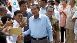 Cambodian Prime Minister Hun Sen, center, of ruling Cambodian People's Party pose for a selfie with his party supporters after a voting in the Senate election Sunday, Feb. 25, 2018. (AP Photo/Heng Sinith)