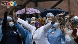 Healthcare workers react to cheers at Brooklyn's Kings County Hospital Center during a 7 o'clock ceremony praising their efforts, April 24, 2020, New York. (AP Photo/Mark Lennihan)