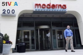 A man stands outside an entrance to a Moderna, Inc., building, Monday, May 18, 2020, in Cambridge, Mass. Moderna announced Monday that an experimental vaccine against the coronavirus showed encouraging results.
