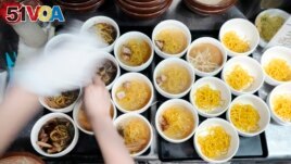 A staff member prepares small bowls of noodles for participants of Tokyo Ramen Tours at Shinbusakiya, a ramen shop that offers Hokkaido classics, at Shibuya district on April 2, 2024, in Tokyo. (AP Photo/Eugene Hoshiko)