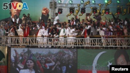 Supporters of Imran Khan (on screens top and R), chairman of the opposition Pakistan Tehreek-e-Insaf (PTI) political party, chant anti-government slogans during his speech at a rally in Karachi September 21, 2014. Protesters led by Imran Khan, a former cricket star, and Tahir ul-Qadri, a firebrand cleric, have been locked in a bitter stand-off with the government since mid-August.  (REUTERS/Akhtar Soomro)