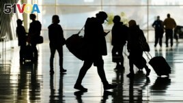 FILE - Passengers walk through Salt Lake City International Airport Tuesday, Oct. 27, 2020, in Salt Lake City. Not as many young adults live far away from where they grew up compared to their parents. (AP Photo/Rick Bowmer)