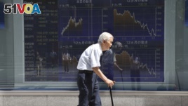 An elderly man walks by an electronic stock board of a securities firm in Tokyo, Aug. 19, 2016.