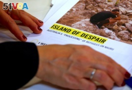 Anna Neistat, senior director for research with Amnesty International, talks to journalists as she holds a copy of a report she co-authored titled 'Island of Despair - Australia's 