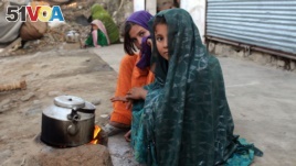 Internally displaced girls warm up by a stove after their family left their village in the Achin district of Afghanistan.