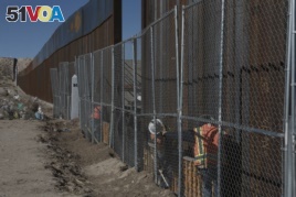 Workers continue work raising a taller fence in the Mexico-US border separating the towns of Anapra, Mexico and Sunland Park, New Mexico, with funding from a 2006 law.