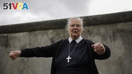 In this Sept. 18, 2019, photo, Sister Brigitte Queisser of the Lutheran Lazarus Order talks in front of concrete remains of the Berlin Wall during an interview with The Associated Press in Berlin