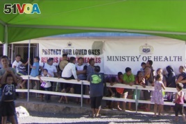 In this November 2019, image from video, children with parents wait in line to get vaccinated outside a health clinic in Apia, Samoa.