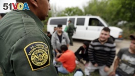 In this Thursday, March 14, 2019, file photo, a Border Patrol agent talks with a group suspected of having entered the U.S. illegally near McAllen, Texas. (AP Photo/Eric Gay, File)