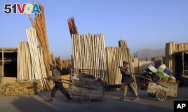 Afghan men pull their carts pass roadside timber stalls in Kabul, Afghanistan, Tuesday, June 21, 2011. (AP Photo/Gemunu Amarasinghe)