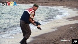 A paramilitary police officer carries the lifeless body of a migrant boy near the Turkish resort of Bodrum early Wednesday, Sept. 2, 2015. (AP Photo/DHA)