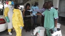 FILE - A health worker sprays a colleague with disinfectant during a training session for Congolese health workers to deal with Ebola virus in Kinshasa, Oct. 21, 2014. The process of removing the full-body protective suit is a prime opportunity for infection if the surface of the gear is contaminated.