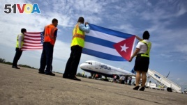 Airport workers receive the JetBlue flight 387 holding a United States, and Cuban national flag, on the airport tarmac in Santa Clara, Cuba, Aug. 31, 2016. 