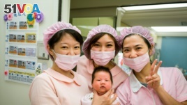 A group of nurses holds a newborn baby. The World Health Organization notes that, globally, there is a huge shortage of nurses and midwives.