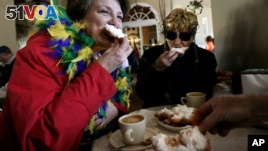 Dressed for Mardi Gras, friends enjoy beignets and coffee at the famous Cafe Du Monde in New Orleans.
