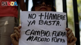 A woman holds a placard that reads 