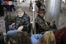 In this Dec. 29, 2014, photo, people use a charging station at McCarran International Airport in Las Vegas.