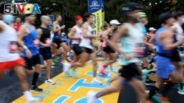 FILE - Runners cross the starting line of the 125th Boston Marathon, Monday, Oct. 11, 2021, in Hopkinton, Mass. (AP Photo/Mary Schwalm, File)