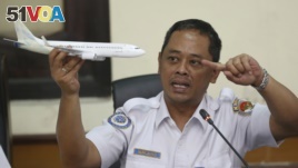 FILE - National Transportation Safety Committee investigator Nurcahyo Utomo holds a model airplane during a press conference on the committee's preliminary findings of the crash of Lion Air flight 610, in Jakarta, Indonesia, Nov. 28, 2018.