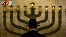 FILE - An Ultra-Orthodox Jewish man stands in front of a menorah on the third eve of Hanukkah, at the Western Wall, Judaism's holiest site in Jerusalem's old city on December 13, 2009. (AP Photo/Sebastian Scheiner, File)