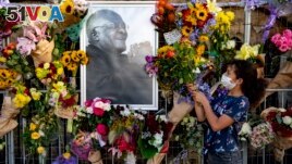 Flowers are placed on a fence surround a portrait of former Anglican Archbishop Desmond Tutu outside St. George's Cathedral in Cape Town, South Africa, Dec. 27, 2021. At midday bells are rung to honor Tutu, a day after his death. (AP Photo)