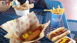A person eats hotdogs and french fries at a Washington Nationals baseball game in Washington, DC.