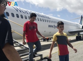 Fourteen-year-old Hermelindo Juarez, right, and his father, Deivin Juarez, step off a chartered flight from the U.S., Tuesday, July 10, 2018 in Guatemala City, Guatemala, after the two were deported.