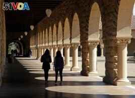 FILE- In this March 14, 2019, file photo students walk on the Stanford University campus in Santa Clara, Calif.