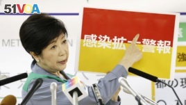 Tokyo Governor Yuriko Koike shows a banner reading 'Infection spread alert' during a news conference on the latest situation of the coronavirus disease (COVID-19) outbreak, in Tokyo, Japan, July 15, 2020, in this photo taken by Kyodo.