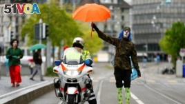 A person dressed as a clown holds an umbrella over a police officer in Switzerland, 2017.