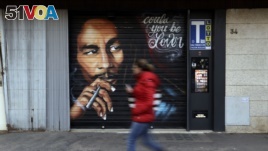 A woman walks past a mural depicting reggae music icon Bob Marley painted on the rolling shutter of a Tobacco shop in Rome, Thursday, Nov. 28, 2018. (AP Photo/Gregorio Borgia)