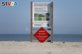 A warning sign against algae bloomsstands on an empty Maumee Bay State Park public beach on Lake Erie in Oregon, Ohio, on Friday, September. 15, 2017.