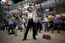 Elderly and middle-age people exercise with wooden weights during a health event to celebrate Japan's 