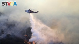 在洛杉矶的曼德维尔峡谷燃烧的盖蒂大火，一架直升机喷水灭火（2019年10月28日）
