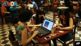 Three young Vietnamese girls use a laptop and smart phones to go online at a cafe in Ha Noi, Viet Nam Wednesday, May 14, 2013. Close to a third of Vietnam's 90 million people are online.