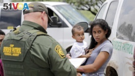 A mother migrating from Honduras holds her 1-year-old child as surrendering to U.S. Border Patrol agents after illegally crossing the border Monday, June 25, 2018, near McAllen, Texas. (AP Photo/David J. Phillip)