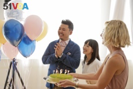 FILE - Marie Kondo, center, looks on as a cake is brought to celebrate her husband Takumi Kawahara's birthday in New York, Wednesday, July 11, 2018. (AP Photo/Seth Wenig)