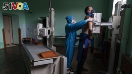 A medic prepares a coronavirus patient for a lung X-ray at a hospital in Stryi, Ukraine, Tuesday, Sept. 29, 2020. (AP Photo/Evgeniy Maloletka)