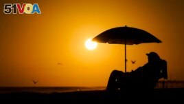 FILE - A person rests under an umbrella as the sun sets, Sept. 12, 2023, in Newport Beach, Calif. European Union scientists said 2023 would be the warmest year on record. (AP Photo/Ryan Sun, File)
