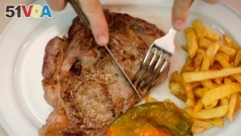 FILE - A beef steak is cut at the Taberna del Gijon restaurant in Madrid, Spain, July 26, 2017. 