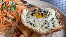 A vegan chorizo egg roll and a meat chorizo egg roll topped with a fried egg and a papaya and carrot slaw is served on Friday, Oct. 14, 2022 at BOCA restaurant in Tucson, Arizona (AP Photo/Terry Tang)