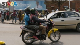 FILE - A passenger rides on a moto-taxi in Kigali, Rwanda, July 30, 2017. Rwanda is introducing electric motorcycles, with more than 600 being built for use in the country.