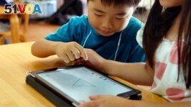 FILE - Children work on a digital program at Coby Preschool in Yoshikawa, suburban Tokyo, on an assignment, which was to draw on a triangle on an iPad, July 12, 2018.