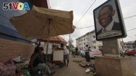 FILE - A street vendor sits near a portrait of Equatorial Guinea's President Teodoro Obiang Nguema Mbasogo in Malabo.
