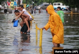 A Filipino man carries a girl as they negotiate a flooded street after a heavy downpour in suburban Quezon city, north of Manila, Philippines on Wednesday, June 17, 2015. AP Photo/Aaron Favila)