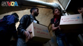 Men unload aid boxes from a Red Crescent aid convoy in the rebel held besieged town of Jesreen, Syria, March 7, 2016.