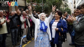 FILE, In this Sunday, Oct. 1, 2017 photo, an elderly lady is applauded as she celebrates after voting at a school assigned to be a polling station by the Catalan government at the Gracia neighborhood in Barcelona, Spain. (AP Photo/Bob Edme, File)
