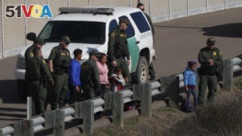 A woman and children stand amidst U.S. Border Patrol agents after crossing illegally over the border wall into San Diego, California, on December 9, 2018. Border security officials say there has been a sharp increase in people seeking to enter the country illegally.