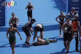 Mexico's Cecilia Perez, center, collapses after competing in a women's triathlon test event at Odaiba Marine Park, a venue for marathon swimming and triathlon at the Tokyo 2020 Olympics, Thursday, Aug. 15, 2019, in Tokyo. Olympic officials say they are concerned about high temperatures in Tokyo during the Games.